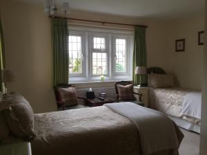 um quarto de hotel com duas camas e uma janela em Coombe House em Bourton on the Water