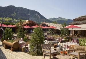 un restaurante con mesas y sillas con montañas al fondo en Les Fermes de Marie, en Megève