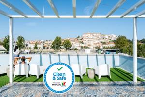 una mujer sentada en un balcón con vistas a la ciudad en JR Studios & Suites I Rius I, en Coímbra