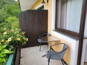 balcón con 2 sillas, mesa y ventana en Pension Waldhof am Stubenbergsee en Stubenberg