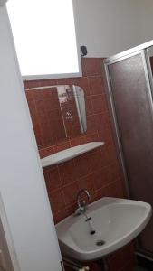 La salle de bains est pourvue d'un lavabo blanc et d'une douche. dans l'établissement Pension Waldhof am Stubenbergsee, à Stubenberg