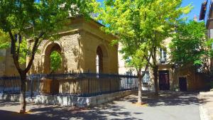 un bâtiment avec une clôture et des arbres devant lui dans l'établissement Le studio d'Agathe centre historique - Confort & Calme, à Valence