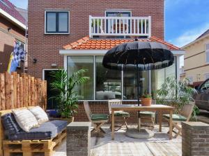 een patio met een tafel en een parasol bij Casa duna close to the beach, city centre, dunes and parking area in Zandvoort