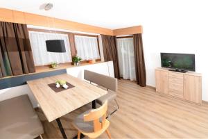 a living room with a wooden table and a television at Apart Alpina Huben in Längenfeld