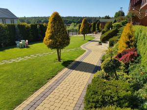 a brick path in a garden with trees and bushes at Willa na wzgórzu in Rusinowo