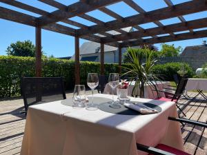 una mesa blanca con copas de vino en el patio en Hôtel SPA Le Tosny, en Épaignes