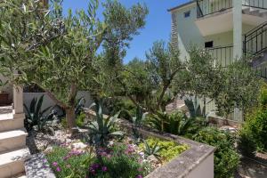 a garden in front of a building with trees and flowers at Apartments Jakic in Hvar