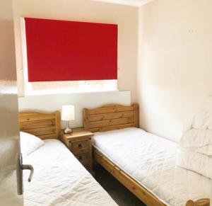 two beds in a room with a red window at Broadside Chalet Park No 90 in Norwich