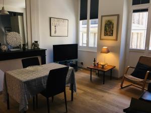 ein Wohnzimmer mit einem Tisch und einem TV in der Unterkunft Joli et agréable studio in Bordeaux