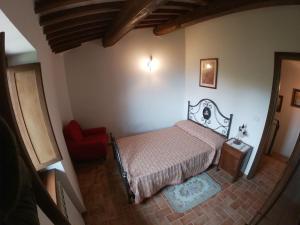 1 dormitorio con 1 cama y 1 silla roja en Castello di Acera, en Campello sul Clitunno