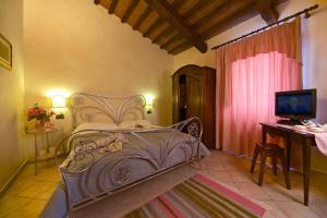 a bedroom with a bed and a desk with a television at Agriturismo Il Felciaione in Massa Marittima