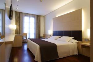 Pokój hotelowy z dużym łóżkiem i biurkiem w obiekcie Hotel Mozart w mieście Valladolid