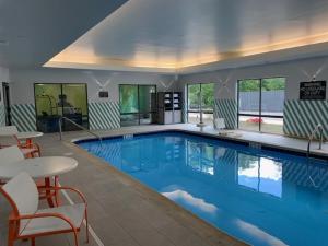 een groot zwembad met stoelen en een tafel bij Holiday Inn - Cheshire - Southington, an IHG Hotel in Cheshire
