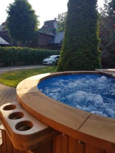 een grote hot tub in de tuin met een bank bij Wooden House near City center in Rīga