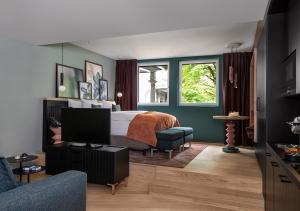 チューリッヒにあるSorell Hotel St. Peterのベッドルーム(ベッド1台、テレビ、ソファ付)