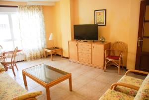 een woonkamer met een flatscreen-tv en een tafel bij Apartamentos Sanxenxo in Sanxenxo