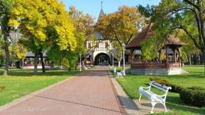 a park with benches in front of a building at Apartman Buba in Palić