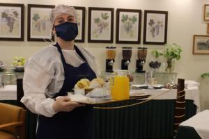 una mujer con una máscara sosteniendo una bandeja de comida en Hotel do Cerrado en Lamego