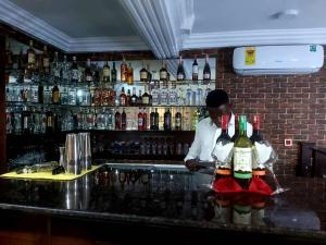 a bartender standing behind a bar with bottles of alcohol at FOKUZZY LODGE in Accra