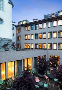 チューリッヒにあるSorell Hotel St. Peterの目の前にテーブルと椅子が置かれた建物