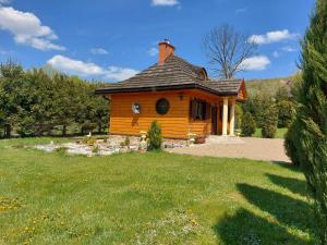 a small wooden house in a field of grass at Bieszczadzki Dworek in Ustrzyki Dolne