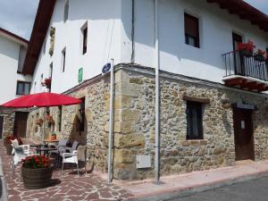 un edificio de piedra con una sombrilla roja y una mesa en Casa Rural Irigoien, en San Sebastián
