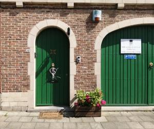 two green doors with a statue of a skeleton on them at Guesthouse La maison de Fille in Diest