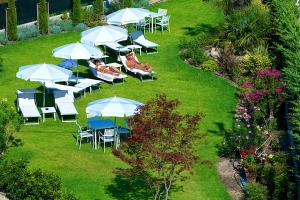 a group of tables and chairs with umbrellas on a lawn at Enjoy Garda Hotel in Peschiera del Garda