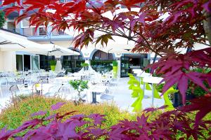an outdoor patio with tables and chairs and flowers at Enjoy Garda Hotel in Peschiera del Garda