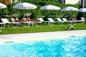 a group of people laying in lawn chairs next to a pool at Enjoy Garda Hotel in Peschiera del Garda