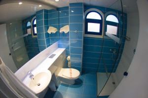 a blue tiled bathroom with a toilet and a sink at Anonymous Beach Hotel (Adults 16+) in Ayia Napa
