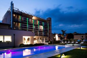 a villa with a swimming pool at night at Enjoy Garda Hotel in Peschiera del Garda