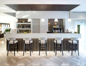 a kitchen with a large white counter with stools at Enjoy Garda Hotel in Peschiera del Garda