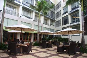 um pátio exterior com mesas e cadeiras com guarda-sóis em The Avenue Plaza Hotel em Naga