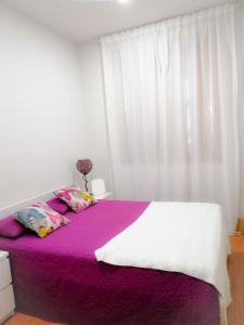 um quarto com uma cama com lençóis roxos e uma janela em 4-As center apartments em Guimarães