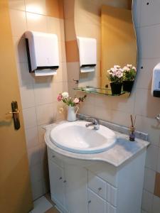 La salle de bains est pourvue d'un lavabo, d'un miroir et de fleurs. dans l'établissement 4-As center apartments, à Guimarães