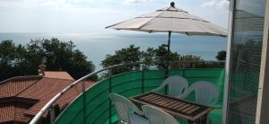 una mesa y sillas en un balcón con sombrilla en Sunny House, en Byala