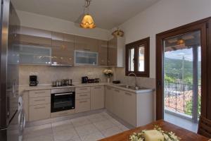 a kitchen with white cabinets and a large window at IATROU HOUSE- villa WITH INCREDIBLE VIEW in Portariá