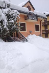 a house with a pile of snow in front of it at Chalet Orchidea in Gallio