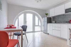 a kitchen with white cabinets and a table with chairs at Apartman Otto in Punat