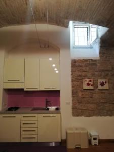 アッシジにあるAppartamento Sant'Apollinareの白いキャビネットとレンガの壁が備わるキッチン