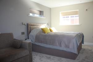 a bedroom with a bed with a chair and a window at Frinton Escapes in Frinton-on-Sea