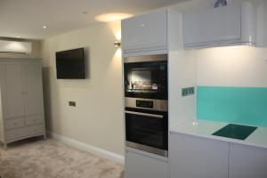 a kitchen with white cabinets and a microwave at Frinton Escapes in Frinton-on-Sea