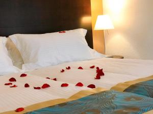 Una cama con pétalos de rosa roja. en SWISS HOTEL LA COURONNE en Avenches