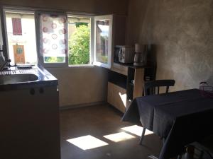 uma cozinha com uma mesa, um lavatório e uma janela em AUX PORTES D'AUBRAC studio 2 personnes em Salgues
