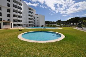 a large swimming pool in the middle of a grass field at Tenis Golf Mar by OCvillas in Quarteira
