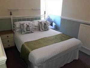 a bedroom with a large white bed with pillows at Ashfields in Llandudno