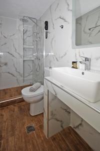 a white bathroom with a sink and a toilet at Akti Kalogria Hotel in Kalogria