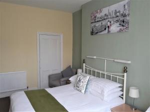 a bedroom with a white bed and a chair at Ashfields in Llandudno