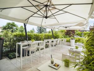 a patio with tables and chairs under umbrellas at Enjoy Garda Hotel in Peschiera del Garda